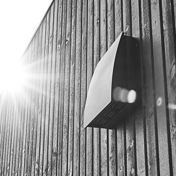 DUKA One DO 30 stormskjerm i svart på avstandsstykke plassert på en svart trevegg